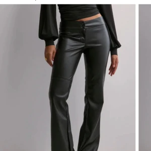 Svarta bootcut byxor i skinnimitation - Snygga svarta skinnbyxor från nelly som är slutsålda. Använda max 3 gånger. Storlek 38. Dom är lågmidjade
