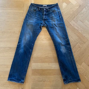 Acne Jeans blå raka jeans 31/32 - Snygga blå jeans från Acne Jeans i klassisk rak modell. Jeansen har en cool tvätt med slitningar och är tillverkade i 100% bomull. Perfekta för dig som gillar en tidlös och avslappnad stil.
