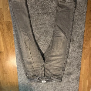 Grå jeans från Jack & Jones 31/30 - Säljer ett par grå jeans från Jack & Jones i klassisk femficksmodell. Jeansen har raka ben och normal passform, tillverkade i bomull med snyggt tvättad look. Perfekta för dig som gillar en stilren och avslappnad vibe.