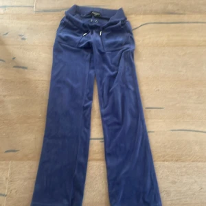 Blå velourbyxor Juicy Couture XXS - Mysiga blå mjukisbyxor från Juicy Couture i velour med snörning i midjan och två bakfickor med guldiga knappar. Klassisk relaxed fit och ribbad midja, perfekta för chill dagar eller när du vill vara extra comfy.helt oanvända 