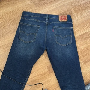 Levi's 502 mörkblå jeans straight fit - Säljer ett par Levi's 502 jeans i mörkblå tvätt med klassiska fem fickor och snygga kontrastsömmar. Modellen har rak passform och normal midja, med Levi's patch och röd etikett bak. Perfekt för dig som gillar tidlös stil och vill ha jeans som funkar till allt. Pris går att diskutera 