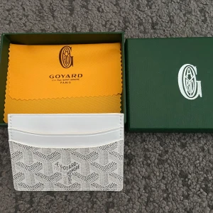 Vit plånbok med snygga mönster - Säljer en stilren vit plånbok med grafiska mönster. Plånboken har flera kortfack och är tillverkad i skinn. Kommer med original ask. Perfekt för dig som vill ha något exklusivt och snyggt i fickan. Helt ny aldrig använd.