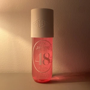 Sol de Janeiro Cheirosa 48 Body Mist - Fräsch och tropisk body mist från Sol de Janeiro, Cheirosa 48. Flaskan är genomskinlig med rosa vätska och vit spraykork. Doften har inslag av guava, solig orkidé och rosa mysk. Perfekt för dig som älskar söta och fruktiga dofter.