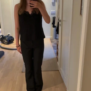 Svarta kostymbyxor med bootcut - Säljer ett par svarta kostymbyxor med bootcut-snitt och låg midja. Byxorna har två fickor bak och är sydda i ett slätt tyg som känns dressat men ändå bekvämt. Perfekta om du vill ha en clean och stilren look.