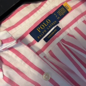 Polo Ralph Lauren Skjorta - Säljer en exklusiv Polo Ralph Lauren skjorta i rosa, storlek S, regular fit. Endast använd en gång – i nyskick! Nypris: 1795 kr. Pris: 800kr. 📍 Finns i Växjö. Kan mötas upp eller skickas. 