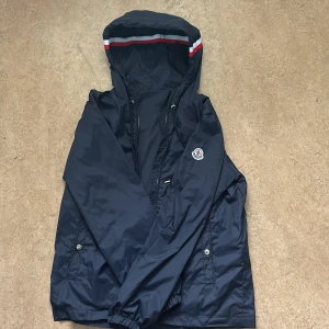 Mörkblå vindjacka från Moncler - Säljer en mörkblå Moncler vindjacka. Jackan är precis som ny. Har använt den 3 gånger. Jackan har NFC vilket betyder att loggan kan skannas. Precis kan diskuteras 