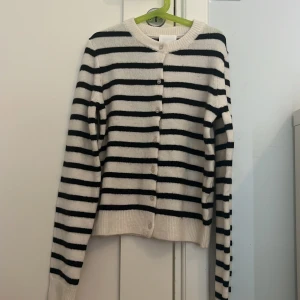 Randig kofta från H&M  - Prislapp kvar, aldrig använd. Snygg kofta från H&M i storlek XS med svartvitt randigt mönster. Tröjan har rund halsringning, långa ärmar och knäppning framtill med små knappar. 