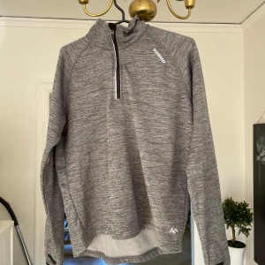 Tränings halfzip - Säljer en gråmelerad fleece-tröja från Karhu i storlek S. Tröjan har half zip framtill, hög krage och långa ärmar. Perfekt för kyliga dagar och träning. Mjuk insida i fleece och diskret logga på bröstet. Snygg och sportig look! Storlek S.