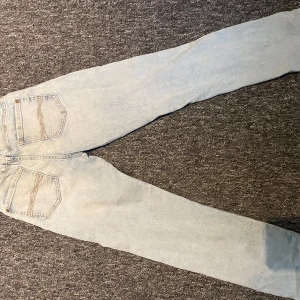 Ljusblå jeans från Next, stl 152 - Säljer ett par ljusblå jeans från Next i klassisk modell med raka ben och snygga kontrastsömmar på bakfickorna. Jeansen  har en normal passform som sitter skönt på kroppen. Perfekta för dig som gillar en clean och enkel stil.