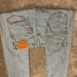 Levi's 501 ljusblå jeans straight fit - Klassiska Levi's 501 jeans i ljusblå tvätt med raka ben och femficksmodell. Jeansen har den ikoniska läderpatchen bak och silverfärgade nitar. Tillverkade i slitstark bomullsdenim och har knappgylf. 