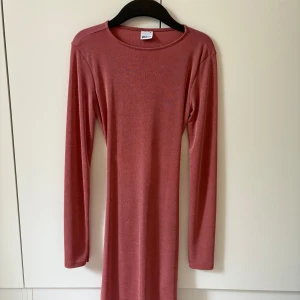 Rosa långärmad klänning Gina Tricot - Snygg rosa långärmad klänning från Gina Tricot med tight passform. Klänningen har öppen rygg och  rynkdetalj baktill. Mjuk och stretchig i materialet, 