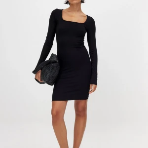 Svart ribbad klänning från NA-KD - Svart, tight ribbad klänning från NA-KD med lång ärm och fyrkantig ringning. Kort modell som sitter snyggt på kroppen. Säljer då den aldrig är använd. 