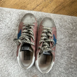 Rosa sneakers från Golden Goose - Golden Goose sneakers i rosa mocka med vit häl och sula, blå stjärndetalj på sidan.