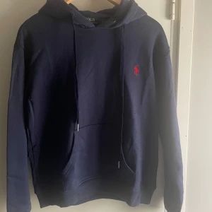 Marinblå hoodie från Polo Ralph Lauren - Säljer en marinblå hoodie från Polo Ralph Lauren, en väldigt efterfrågad hoodie. Hoodie är näst in till ny skick/använd fåtal gånger. Nypris ligger på 2000 kronor och jag säljer denna för endast 900 kronor, pris kan även diskuteras vid snabb affär 😁 skriv ifall du har några frågor! 