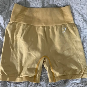 Gula seamless shorts från Gymshark - Snygga gula seamless shorts från Gymshark med hög midja och tight passform. Tillverkade i ett stretchigt material. Diskret mönster längs sidorna,  Material: 93% nylon, 7% elastan.