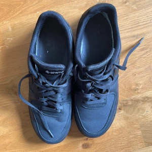 Nike Air Force 1 Gore-Tex svarta sneakers - Svarta Nike Air Force 1 sneakers med Gore-Tex-material som gör dem vattentäta. Klassisk låg modell med snörning, rund tå och platt sula. Swoosh-logga på sidan och Gore-Tex-detalj på hälen. Perfekta för dig som vill ha stilrena och tåliga sneakers. Liten skada i hälen men inget som påverkar.