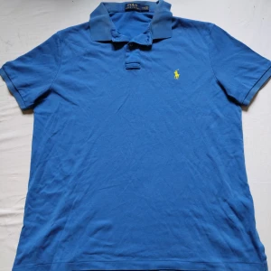 Marinblå Ralph Lauren piké  - Tjo gubbar! En fet Ralph Lauren piké i fin blå färg med märket i gult. Väldigt bra skick, storlek L, perfekt för just dig 😉. Kolla gärna profilen för mycket mer Ralph Lauren kläder och följ gärna också ❤️ ha de göttttttt 🥳.