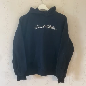 Svart hoodie Sweet Sktbs XXS - Svart hoodie från Sweet Sktbs i storlek XXS. Tröjan har broderad vit logga på bröstet, stor huva och klassisk känguruficka framtill. Mjuk och skön bomullskänsla, perfekt för chill dagar. Långärmad och med ribbade muddar vid ärmslut och nederkant.