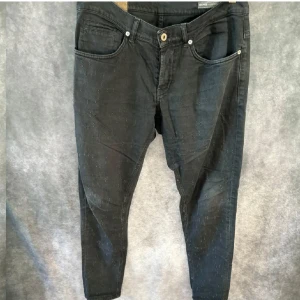 Svarta jeansbyxor från dondup - Svarta jeansbyxor från dondup med klassisk femficksdesign och knappgylf. Byxorna har en smal passform och är tillverkade i jeansmaterial. Snygga detaljer med  dondup loggan på bakfickan och röd märkning i linningen.