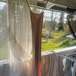 Lång beige slipklänning - Säljer en lång, tunn slipklänning i beigea toner. Klänningen har smala axelband och en rak, figurnära passform. Perfekt för varma dagar och har en enkel, stilren look.