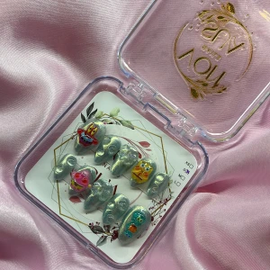 JellyJam(S);Short Almond - Snygga gelé press on-naglar i silverblå cateyemetallic med 3D-motiv av Svampbob, Patrick, Bläckvard och Herr Krabba. Naglarna är i en kort mandelform och har en glansig finish. Perfekt för dig som vill ha en unik och lekfull look med tecknad design. I storlek S: 15 mm, 11,5 mm, 12 mm, 11 mm, 9 mm 