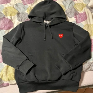 Cdg Hoodie - En svart hoodie från Comme des Garçons Play, som inte längre kommer till användning men har inga defekter. Tröjan är i storlek M men är liten i storleken och passar mer som S enligt mig. Nypris 2349 kr. Vid eventuella frågor är det bara att höra av sig.