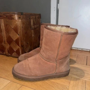 Bruna UGG boots  - Mysiga bruna UGG boots i klassisk modell! Skorna har platt sula och rund tå, perfekta för kalla dagar. UGG-logga bak på hälen och grovt mönstrad yttersula för bra grepp. De är i andvänt men bra skick och fortfarande otroligt mjuka och varma! Hör gärna av er vid frågor eller intresse och kolla in resten jag säljer! 
