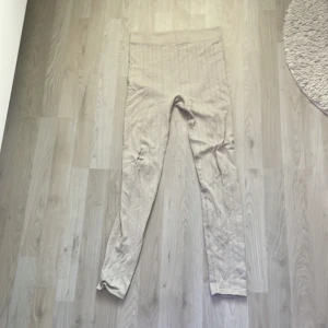 Beige stickade leggings från H&M - Säljer ett par beige stickade leggings från H&M i storlek S. De har ett snyggt kabelstickat mönster och bred resår i midjan för extra komfort. Perfekta för en chill och avslappnad look.