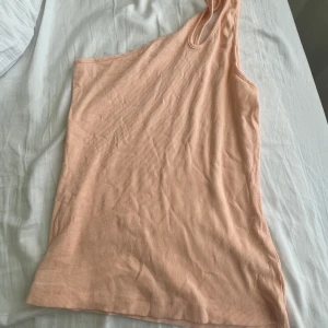 Två toppar  - Ett sett två toppar som är enarmade. I grå och orange. Barn storlek 158, stor i storlek 