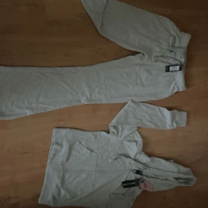 Ljusgrå hoodie från PrettyLittleThing - Ljusgrå hoodie med dragkedja och huva från PrettyLittleThing. Tröjan har långa ärmar, snörning i huvan och praktiska fickor framtill. Perfekt för chill dagar och enkel att matcha med andra plagg. Passar storlek XS också. Köptes för 430kr