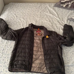 Parajumper ugo - Säljer en svart dunjacka från Parajumpers med klassisk quiltad design och dragkedja framtill. Jackan har lång ärm, hög krage och snygga detaljer som gul rem vid halsen. Perfekt för kyliga dagar och riktigt lätt att bära. Pris kan diskuteras.