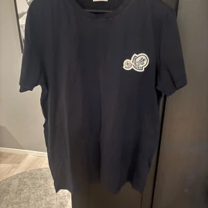 Mörkblå Moncler t-shirt i bomull - Säljer en moncler t shirt i storlek M passar även S. Nypris runt 3 tusen. Qr koden fungerar och kan gå ner i pris vid snabb affär