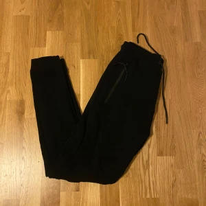 Svarta mjukisbyxor Pull&Bear XS - Svarta mjukisbyxor från Pull&Bear i storlek XS. Byxorna har resår och snörning i midjan samt dragkedjeförsedda fickor. Perfekta för chill dagar eller när du vill vara bekväm men ändå se snygg ut.