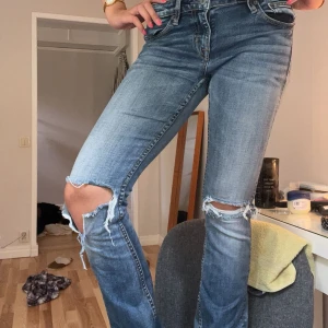 Ljusblå slitna jeans med hål på knäna - Säljer ett par ljusblå jeans med snygga slitningar och hål på båda knäna. Jeansen har klassisk femficksdesign, normal passform och är bootcut! Perfekta för en avslappnad och trendig look. Vill bli av med allt så fort jag kan därav priset!!💓💓Bär S och de sitter perfekt på mig🍓obs!! Den har en liten fläck 🌸se bild 