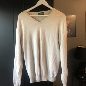 Alan Paine tröja - Snygg beige v-ringad tröja från Alan Paine i mjuk bomull. Klassisk modell med ribbade muddar vid ärmslut och nederkant. Perfekt för lager-på-lager och passar till både jeans och chinos. Enkel och stilren design som funkar året runt. Mitt pris: 300kr. Storlek: EUR50