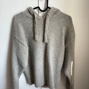 Grå stickad hoodie med huva från Zara  - Mysig grå stickad hoodie med huva och snörning från Zara. Tröjan har ribbade muddar vid ärmslut och nederkant, samt en avslappnad passform. Användes ett antal gånger, men är i super bra skick. 