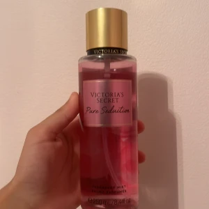 Pure Seduction - En snygg och fräsch body mist från Victoria's Secret i doften Pure Seduction. Flaskan är genomskinlig med rosa vätska och har en guldig kork. Rymmer 250 ml och har en feminin, modern look som passar perfekt i väskan.