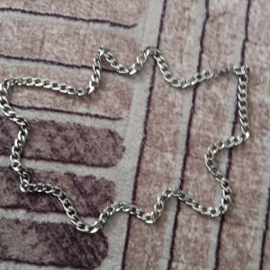 Kedjehalsband i silverfärg - Snyggt halsband med grov kedja i silverfärg. Länkarna är platta och blanka, vilket ger ett coolt och stilrent intryck. Perfekt accessoar för att lyfta din outfit med en modern touch.