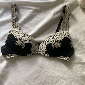 Svart spets-bh med blommig brodyr - Supersnygg svart bh med vit blommig spets och broderade detaljer från intimissimi. Axelbanden är dekorerade med samma spets och bh:n har en klassisk form med bygel. Perfekt för dig som vill ha något extra under tröjan. Jag säljer denna bh för köpte fel storlek tyvärr ❣️