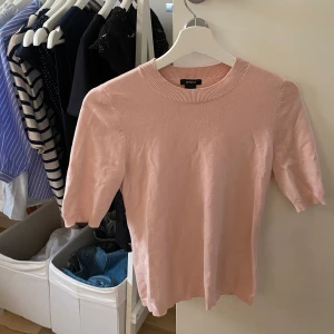 Ljusrosa stickad topp från Lindex - Supersöt ljusrosa stickad topp från Lindex med rund halsringning och korta ärmar. Perfekt för dig som gillar en enkel men ändå stilren look. Mjuk och skön, passar till både jeans och kjol.
