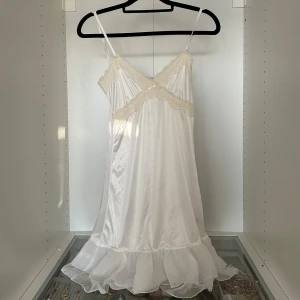 Vit klänning med volanger - Superfin vit klänning som är lite genomskinlig med volander lämgst ned. Såså vacker och köpt i Bangkok på en secondhand för 1200 Baht = 353kr. Lent material så skulle nästan säga att det är som en nattlinne-klänning.