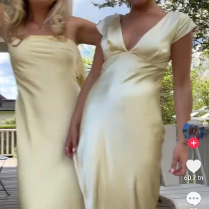 Ljusgul långklänning med v-ringning - Superfin långklänning i ljusgul satin-look med djup v-ringning och korta ärmar. Klänningen har en figurnära passform och faller snyggt längs kroppen. Perfekt för sommarens speciella tillfällen och ger en lyxig känsla med sitt glansiga material. Helt ny och aldrig använd endast provad, har lapparna kvar. Är köpt från hellomolly i Australien och den är helt slutsåld. 