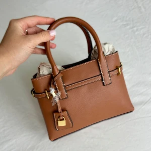 Brun handväska med gulddetaljer från Mango - Snygg brun handväska från Mango i slät skinnimitation med vita kontrastsömmar och guldfärgade metalldetaljer. Väskan har två handtag, dekorativt hänglås och stilren, boxig form.  Ny, aldrig använd med prislapp kvar 💕