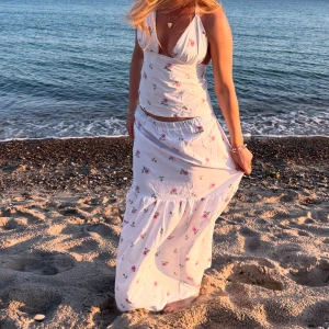 Vit långklänning med blommigt mönster - Supersöt egen sytt sett med en topp och långkjol. 💞Delarna kan köpas separat. Passar ca xs-m eftersom kjolen är stretchig i midjan och toppen har band man knyter. Jag är 162 cm för referens. Ställ gärna frågor! 🩷🌸