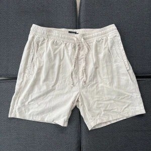 Linne-shorts, storlek L - Lätta och sköna beiga shorts från 157 med elastisk midja och snörning. har två sidofickor och en bakficka, perfekt för chill dagar. Materialet känns mjukt och passar grymt till varma sommardagar.