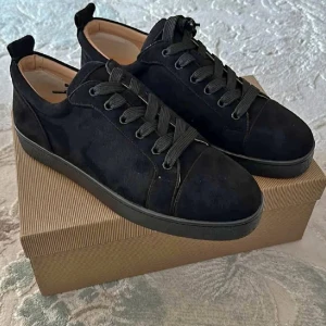 Svarta mockasneakers från Louboutin - Snygga svarta sneakers i mocka från Christian Louboutin med klassisk röd sula och svarta snören. Skorna har rund tå och platt sula, samt beige innersida för extra kontrast. Perfekta för dig som vill ha en stilren men ändå lyxig look.