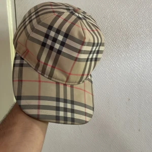 Burberry keps beige M passar som S också - Snygg keps från Burberry. Justerbar baktill med svart spänne och tydlig Burberry London England-patch. Perfekt accessoar för att lyfta din stil på sommarn.