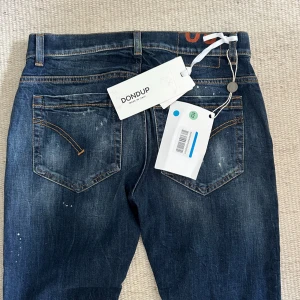 Dondup George jeans - Säljer nu ett par helt nya Dondup George jeans. Färg Mörkblå. Storlek W30 och längden på jeansen från midjan och ner är 103 cm. Passformen är skinny fit vilket ungefär motsvarar slim fit. Om du har några funderingar så är det bara att fråga på! ❇️