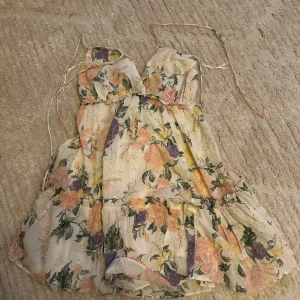 Blommig kortklänning från Gina Tricot - Supersöt kortklänning med blommigt mönster i pastelliga toner av rosa, gul och lila. Klänningen har smala axelband, omlottkänsla vid bysten och volangdetaljer. Perfekt för sommarens alla tillfällen!