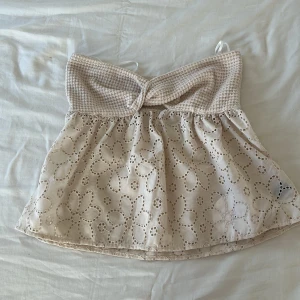 Beige broderad linnetopp med spets - Supersöt beige linnetopp. Virkad överdel. Nedre delen är i bomull med broderade blommor och spetsdetaljer. Perfekt för varma dagar. Lätt och luftig modell som är riktigt skön på sommaren.